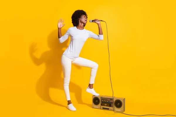 Foto de tamaño completo de la señora de piel oscura emocionada despreocupada cantando pierna en boombox aislado en el fondo de color amarillo — Foto de Stock