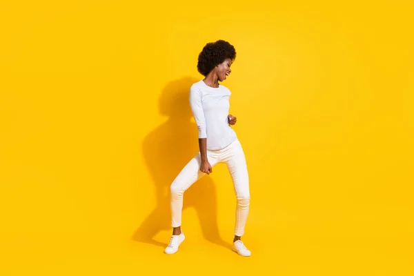 İyimser, havalı, kısa saçlı bayan dansının tam boy fotoğrafı. Sarı arka planda izole edilmiş beyaz kazak pantolonları giyin. — Stok fotoğraf
