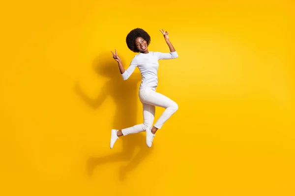 Foto corpo pieno di attraente giovane donna pelle scura saltare mostra v-segni isolati su sfondo di colore giallo — Foto Stock