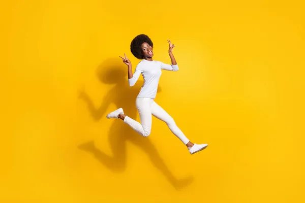 Tam boy profil fotoğrafı koyu tenli kızın yukarı zıplaması parlak sarı arka planda izole edilmiş v işaretini göster — Stok fotoğraf