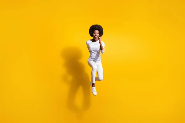 全尺寸的非裔美国可爱女人跳起来的照片，在明亮的黄色背景下与你隔离 — 图库照片