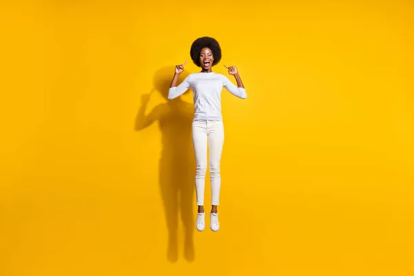 Teljes hosszúságú fotó boldog barna afro amerikai lány ugrik fel pont haj elszigetelt sárga színű háttér — Stock Fotó