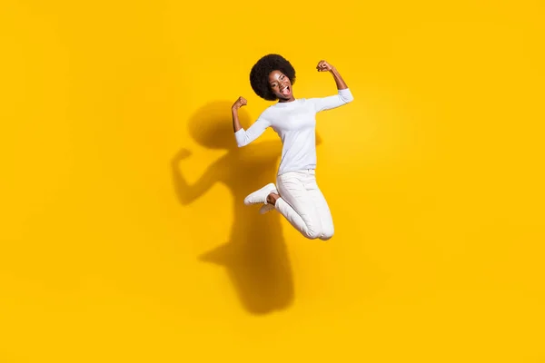 Foto de corpo inteiro de forte mulher afro-americana feliz mostrar músculos saltar isolado no fundo de cor amarela — Fotografia de Stock
