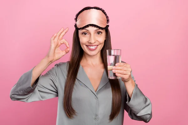 Portrait of attractive cheerful woman drinking water showing ok-sign good morning isolated over pink pastel color background — Stock Photo, Image