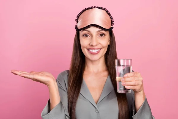 Portrait of attractive cheerful woman drinking water holding copy space advert isolated over pink pastel color background — Stock Photo, Image