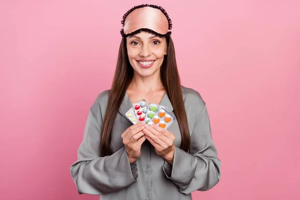 Ritratto di attraente donna allegra che tiene pillole cura insonnia isolato su sfondo rosa pastello — Foto Stock
