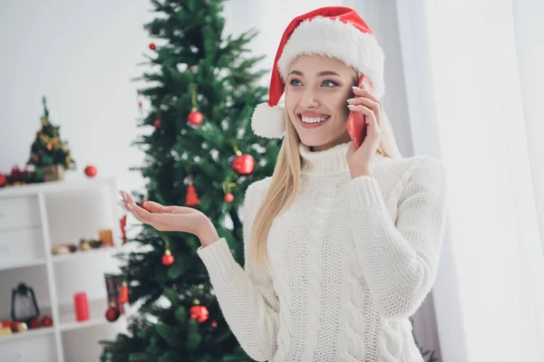 Neşeli genç bir kadının fotoğrafı mutlu mutlu bir gülümseme konuş cep telefonu iç mekanda Noel Baba şapkası giy. — Stok fotoğraf