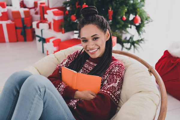 Porträtt av attraktiv glad flicka sitter i stol kramar bok festlig dag december på inredda hem inomhus — Stockfoto