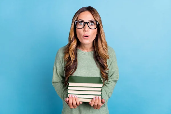 Foto porträtt kvinna bär glasögon hålla bok högen stirrar förvånad isolerad pastell blå färg bakgrund — Stockfoto