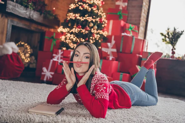 Photo pleine grandeur de jeune femme ludique assis sur le sol porter de nouvelles chaussettes année pull jeans à la maison seul la veille de Noël — Photo