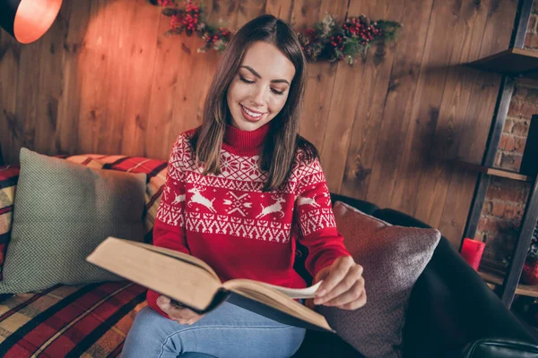 Foto de bonita mujer joven vestida suéter rojo leyendo historias de año nuevo sonriendo en el interior habitación casa — Foto de Stock
