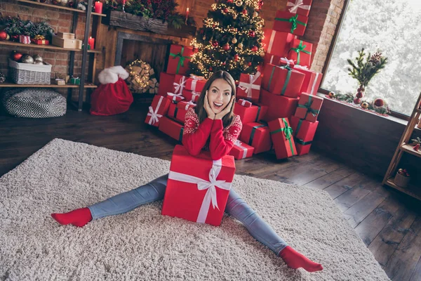 Foto di bella impressionato giovane donna vestita maglione rosso in possesso di nuovo anno regalo scatola mani guance sorridente casa interna stanza — Foto Stock