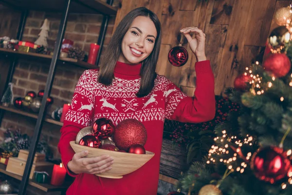 Фото блискучої привабливої молодої леді носить червоний пуловер, усміхнений прикрасою ялинки в приміщенні домашньої кімнати — стокове фото