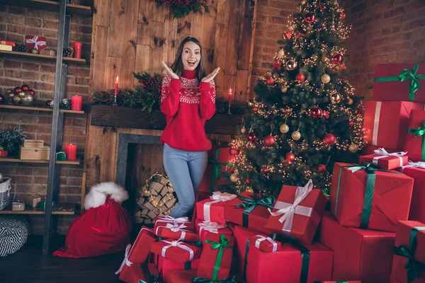 Etkilenmiş genç bir bayanın fotoğrafı kırmızı kazak giyer, gülümser ve ev içinde noel ağacının altında hediyeler alır. — Stok fotoğraf