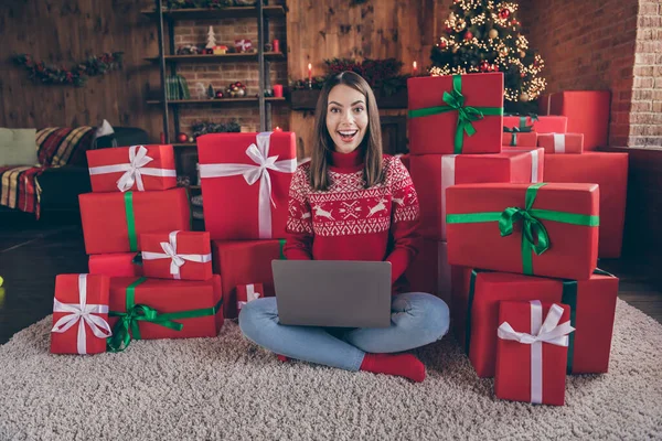 Foto av vacker attraktiv ung dam bära röd pullover ler njuter jul skriva modern enhet inomhus hus hem rum — Stockfoto