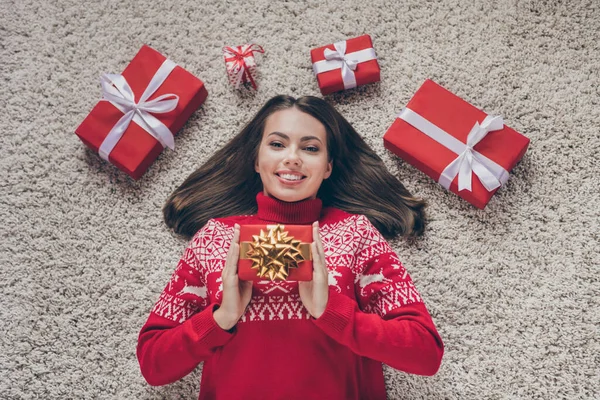 Kırmızı kazaklı, rüya gibi genç bir kadının elinde yeni yıl hediyeleri salonda gülümserken fotoğrafı. — Stok fotoğraf