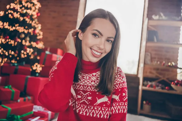 Фото очаровательной молодой женщины, одетой в красный свитер, наслаждающейся новым годом, улыбающейся в помещении дома — стоковое фото