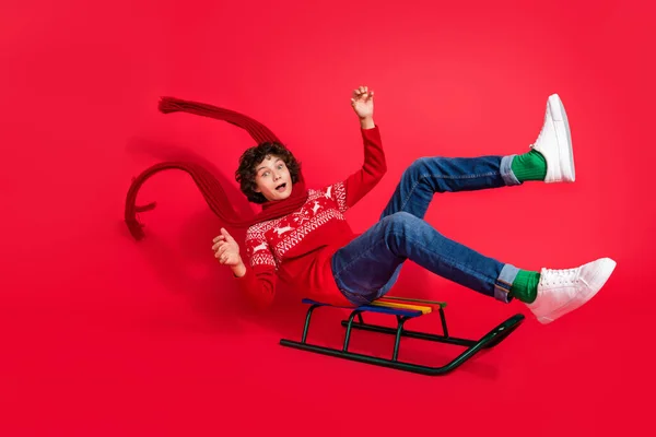 Foto di divertente funky escisso ragazzo corsa slitta godere di inverno indossare cervo ornamento maglione sciarpa isolato colore rosso sfondo — Foto Stock