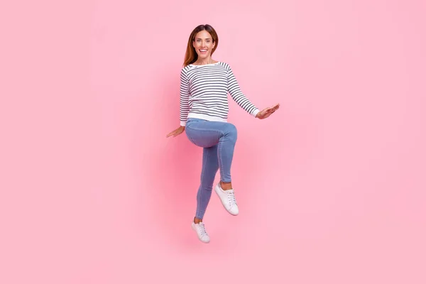 Foto de adorable encantadora mujer joven vestida a rayas pulóver saltando alto caminando aislado color rosa fondo —  Fotos de Stock