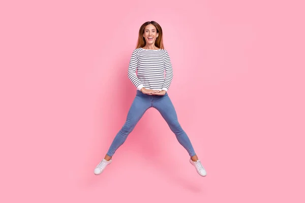 Full size photo of young funky brown hairdo lady jump wear shirt jeans sneakers isolated on pink background — Stock Photo, Image