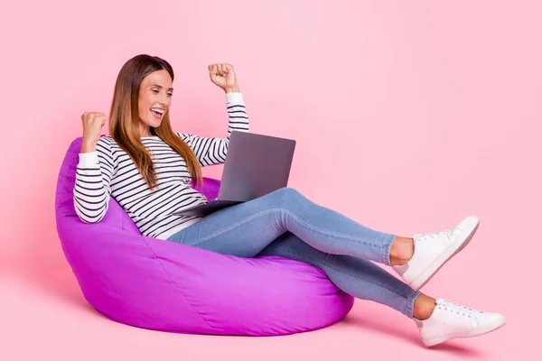 Foto profil ukuran penuh dari wanita berambut coklat dewasa. Terlihat seperti laptop. Duduk memakai celana jeans yang diisolasi dengan latar belakang warna merah muda. — Stok Foto