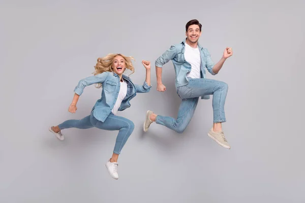 Foto van funky sportieve paar springen haast run snelle slijtage casual jeans outfit geïsoleerde grijze kleur achtergrond — Stockfoto