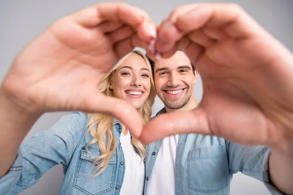 Foto do jovem casal feliz sorriso positivo mostrar dedos coração figura amor romântico isolado sobre fundo de cor cinza — Fotografia de Stock