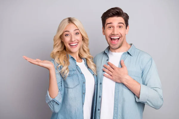 Zdjęcie młodej pary szczęśliwy pozytywny uśmiech trzymać za rękę oferta produktów sprzedaż reklamy sugerują izolowane na szarym tle koloru — Zdjęcie stockowe