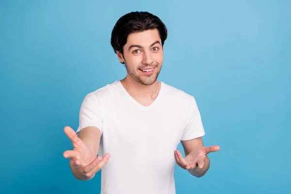 Photo of hospitable charismatic guy stretch hands invite come wear white t-shirt isolated blue color background — Stock Photo, Image