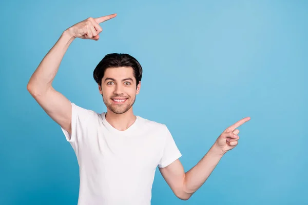 Φωτογραφία του θετικού άντρα δείχνουν δάχτυλα κενό χώρο προωθήσει την καινοτομία πώληση φορούν λευκό t-shirt απομονωμένο μπλε χρώμα φόντο — Φωτογραφία Αρχείου