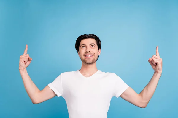 Foto de chico confiable de ensueño indican dedos espacio vacío buscar ropa blanca camiseta aislado color azul fondo —  Fotos de Stock