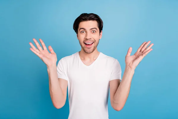 Foto von überrascht erstaunt funky Kerl heben die Hände omg Reaktion tragen weißes T-Shirt isoliert blaue Farbe Hintergrund — Stockfoto
