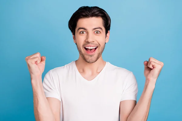 Foto de campeón chico levantar los puños celebrar la victoria levantar los puños usar camiseta blanca aislado fondo de color azul —  Fotos de Stock