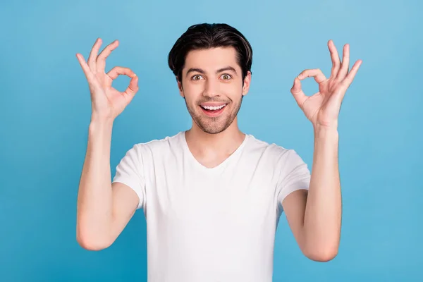 Foto de tipo confiable emocionado levantar las manos muestran gesto okey usar camiseta blanca aislado fondo de color azul — Foto de Stock