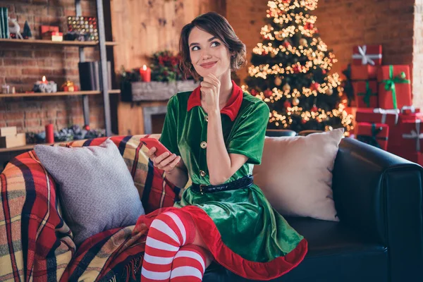 Photo de intelligent esprit réfléchi dame tenir téléphone penser doigt menton porter costume d'elfe dans la maison décorée à l'intérieur — Photo