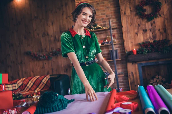 Photo de brillante drôle jeune femme porter des vêtements elfe coupe ciseaux emballage nouvelle année cadeau souriant intérieur maison maison chambre — Photo