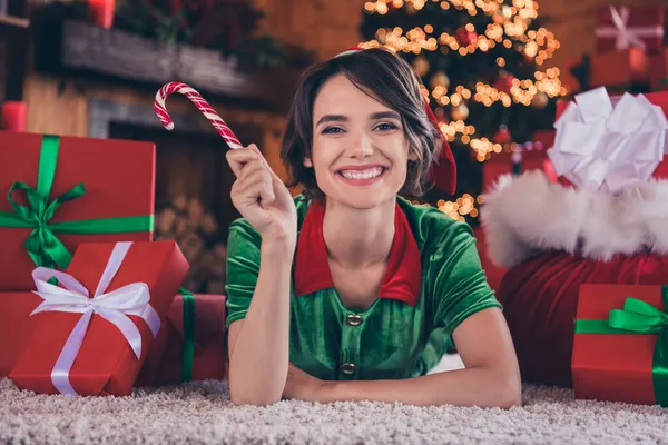 Foto van dromerige zoete jonge dame dragen elf kleren liggen vloer houden lolly glimlachen binnen huis kamer — Stockfoto