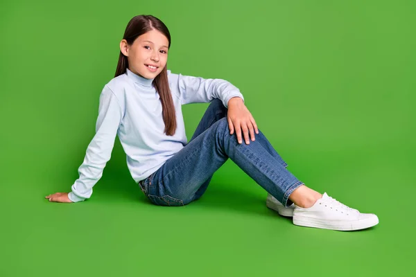 Foto de colegiala bastante dulce usar cuello alto azul sentado piso que descansa sonriendo aislado color verde fondo —  Fotos de Stock