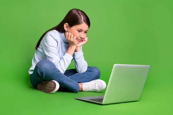 Fotografie zasněné roztomilé školní dívka oblečená modrý rolák sledování filmu moderní gadget prázdný prostor s úsměvem izolované zelené barvy pozadí — Stock fotografie