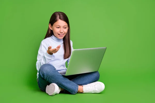 Fotografie legrační krásné školní dívka oblečená modrý rolák mluví moderní gadget prázdný prostor usmívá izolované zelené barvy pozadí — Stock fotografie