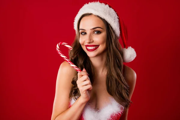 Фотопортрет красивої усміхненої жінки, що тримає цукеркову тростину в одній руці ізольовано на яскраво-червоному тлі — стокове фото