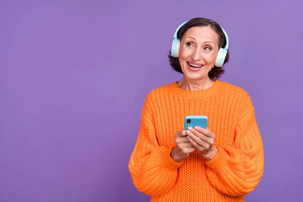 Foto de mujer madura emocionada uso blogger smartphone escuchar auriculares de música aislados sobre fondo de color púrpura —  Fotos de Stock