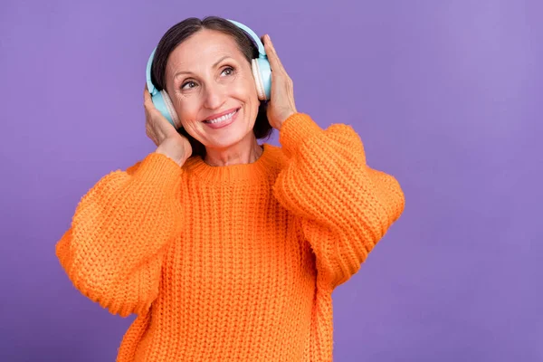 Foto de alegre anciana divertirse escuchar música auriculares de radio excitado buscar espacio vacío aislado sobre fondo de color violeta —  Fotos de Stock