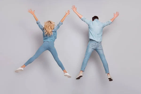 Traseira visão traseira foto do casal salto levantar as mãos desgaste casual jeans roupa isolado cinza cor fundo — Fotografia de Stock