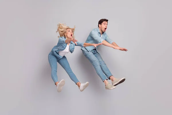 Foto de louco chocado sem palavras casal salto vento soprar desgaste casual jeans roupa isolado cinza cor fundo — Fotografia de Stock