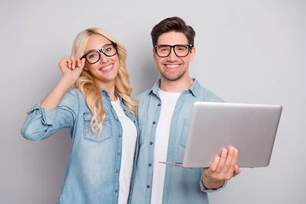 Φωτογραφία από γλυκό αξιολάτρευτο νεαρό ζευγάρι ντυμένα τζιν πουκάμισα γυαλιά κρατώντας σύγχρονη gadget απομονωμένο γκρι χρώμα φόντο — Φωτογραφία Αρχείου