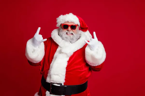 Retrato de atractivo loco Santa mostrando el símbolo del cuerno que se divierte ocasión de año nuevo aislado sobre fondo de color rojo brillante — Foto de Stock