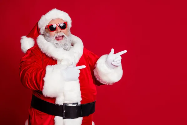 Фото промоутера пенсионера смешной человек прямой палец пустое пространство носить костюм Санта шляпа изолированный красный цвет фона — стоковое фото