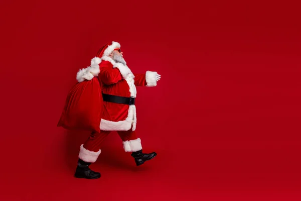 아주 쿨 한 산타 클로스의 사진붉은 색 의상을 입고 검은 눈동자로 걷고 선물을 들고 가는 모습은 텅 빈 공간에 붉은 색 배경을 담고 있다 — 스톡 사진