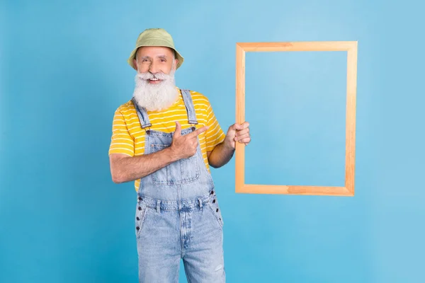 Фото пожилого человека счастливая положительная улыбка точка палец деревянная рамка реклама промо посоветовать изолированы на синем фоне цвета — стоковое фото